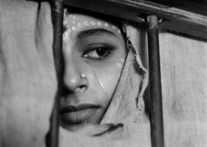 Aparna on the day of the wedding looking through a torn curtain